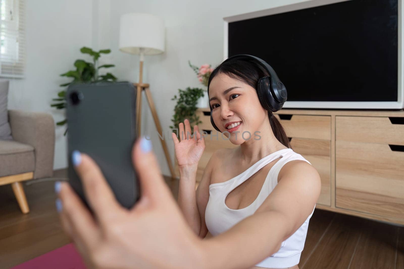 Capturing a moment of self-love, a woman smiles at her phone while practicing yoga, celebrating her fitness journey with a joyful expression.