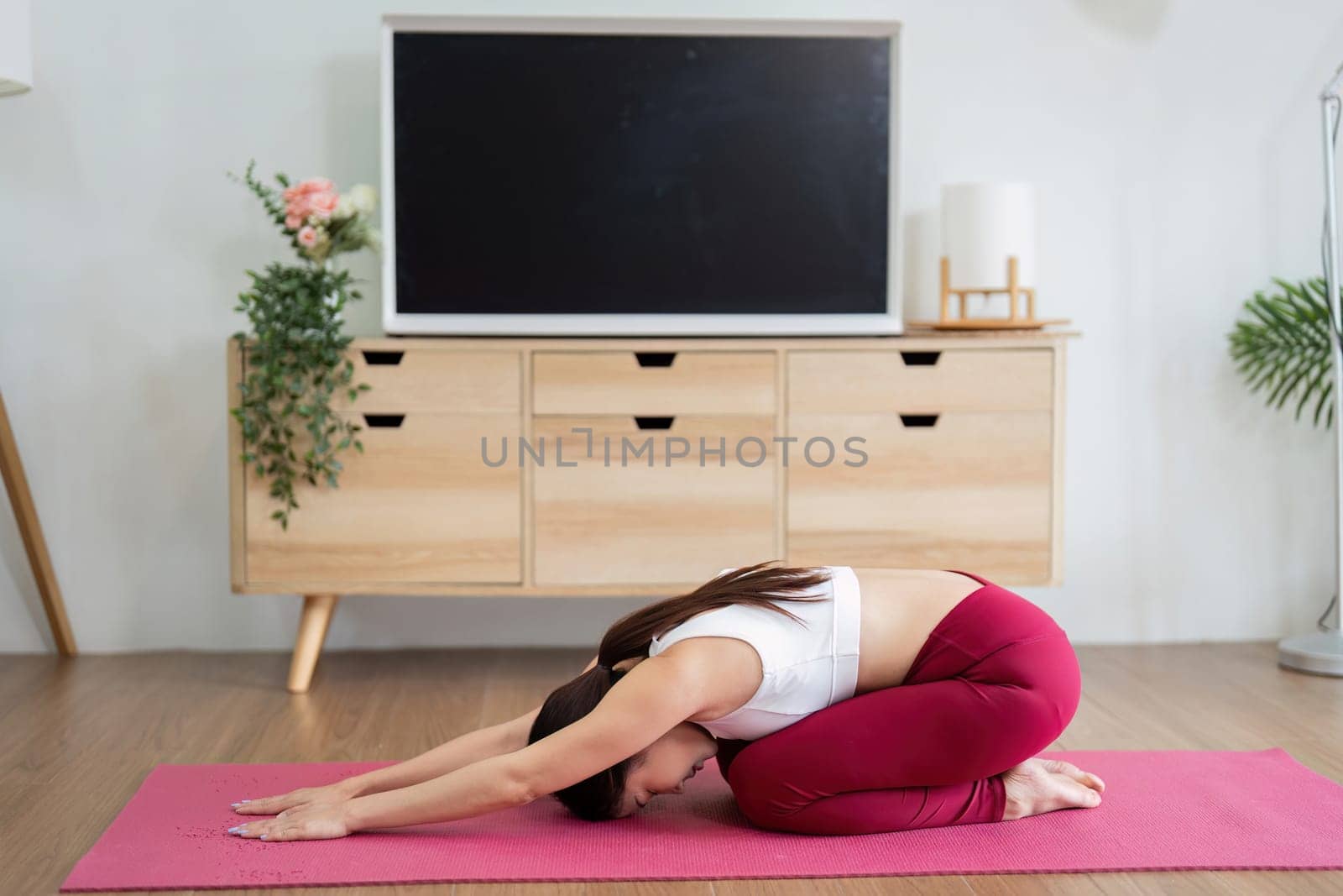 A woman is in child pose, emphasizing relaxation and mindfulness. This yoga pose is perfect for unwinding and enhancing mental clarity.