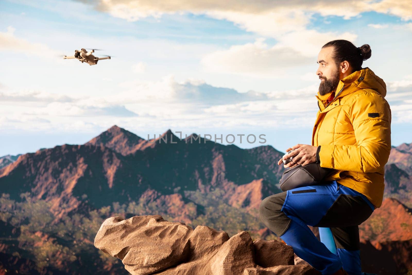 Modern traveler creating content and filming the valley with his drone, climbing on top of a high altitude mountain range. Hiker enjoying the landscape scenery, remote control.
