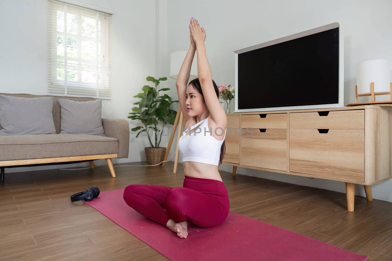 Practicing flexibility, the woman stretches her arms overhead in a tranquil yoga session, finding balance and inner strength.