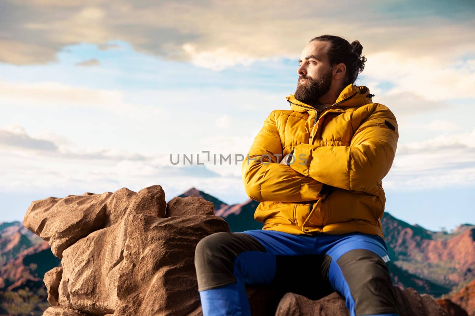 Hiker traveler pauses to admire the panoramic mountain scenery on the hill top, endless sky and rocky peaks creating a breathtaking backdrop for mental clarity. Adventure seeker outdoors.