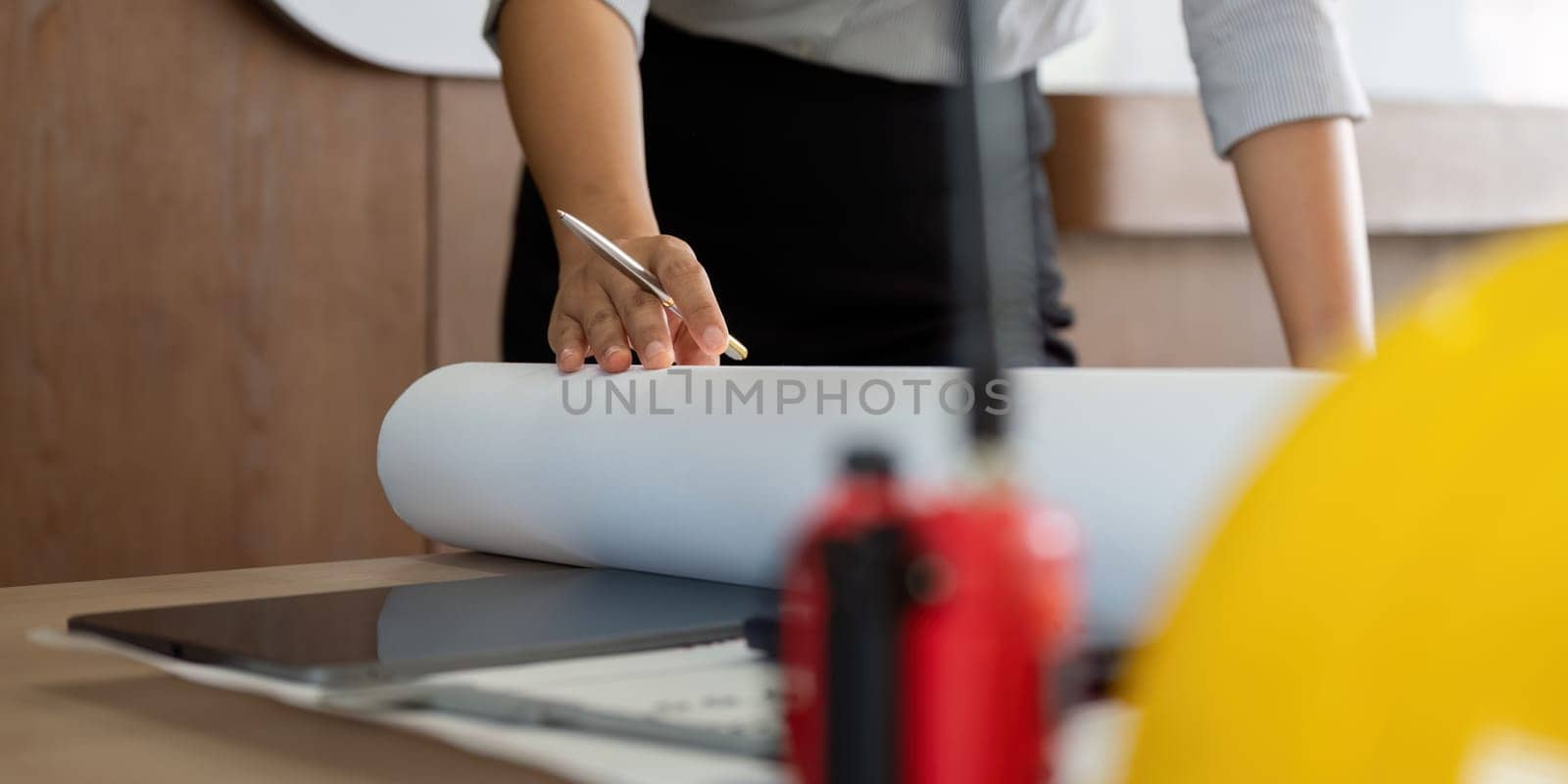 An architect prepares a large blueprint, emphasizing the attention to detail necessary in design. This image captures the dedication and focus required for successful project execution.