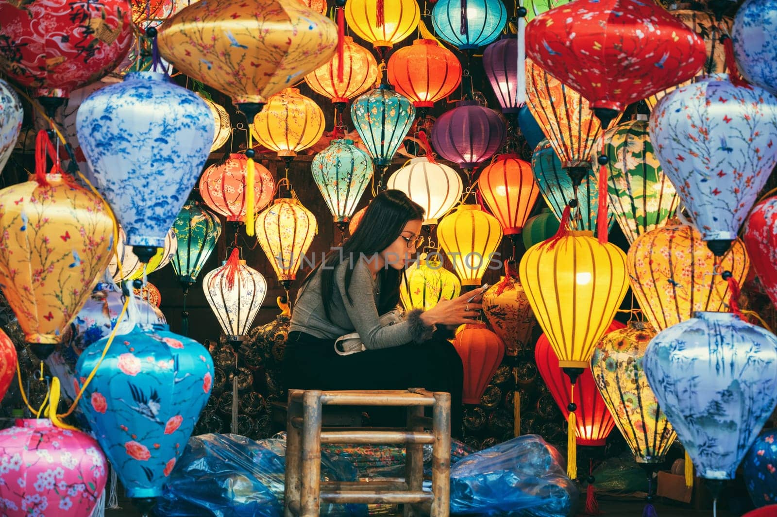 A young Vietnamese girl selling Chinese silk lanterns at Asian night market in Hoi An in Vietnam in Asia. Hoi An, Vietnam - December 1, 2024