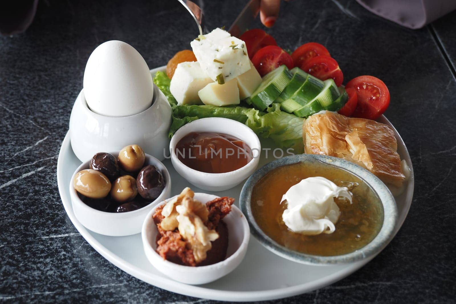 turkish breakfast spread features vegetables, cheese, and olives on a plate.