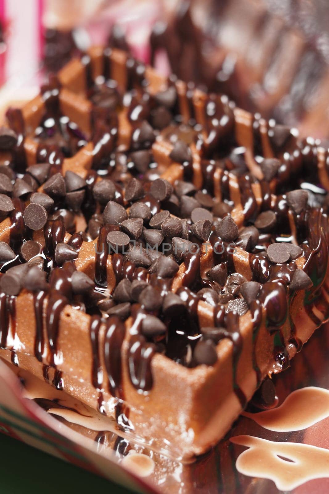 Chocolate waffle topped with chocolate chips and drizzled with syrup.