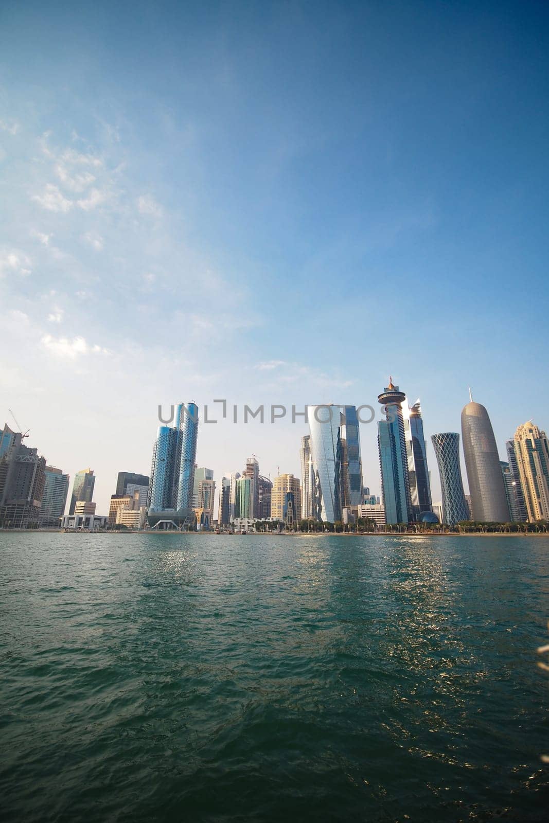 A sunny day showcases a modern skyline along the waterfront.