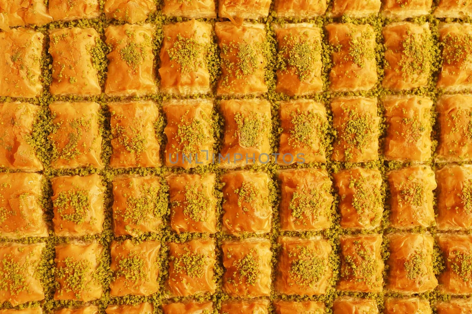 Rows of sweet baklava topped with pistachios attract market visitors.