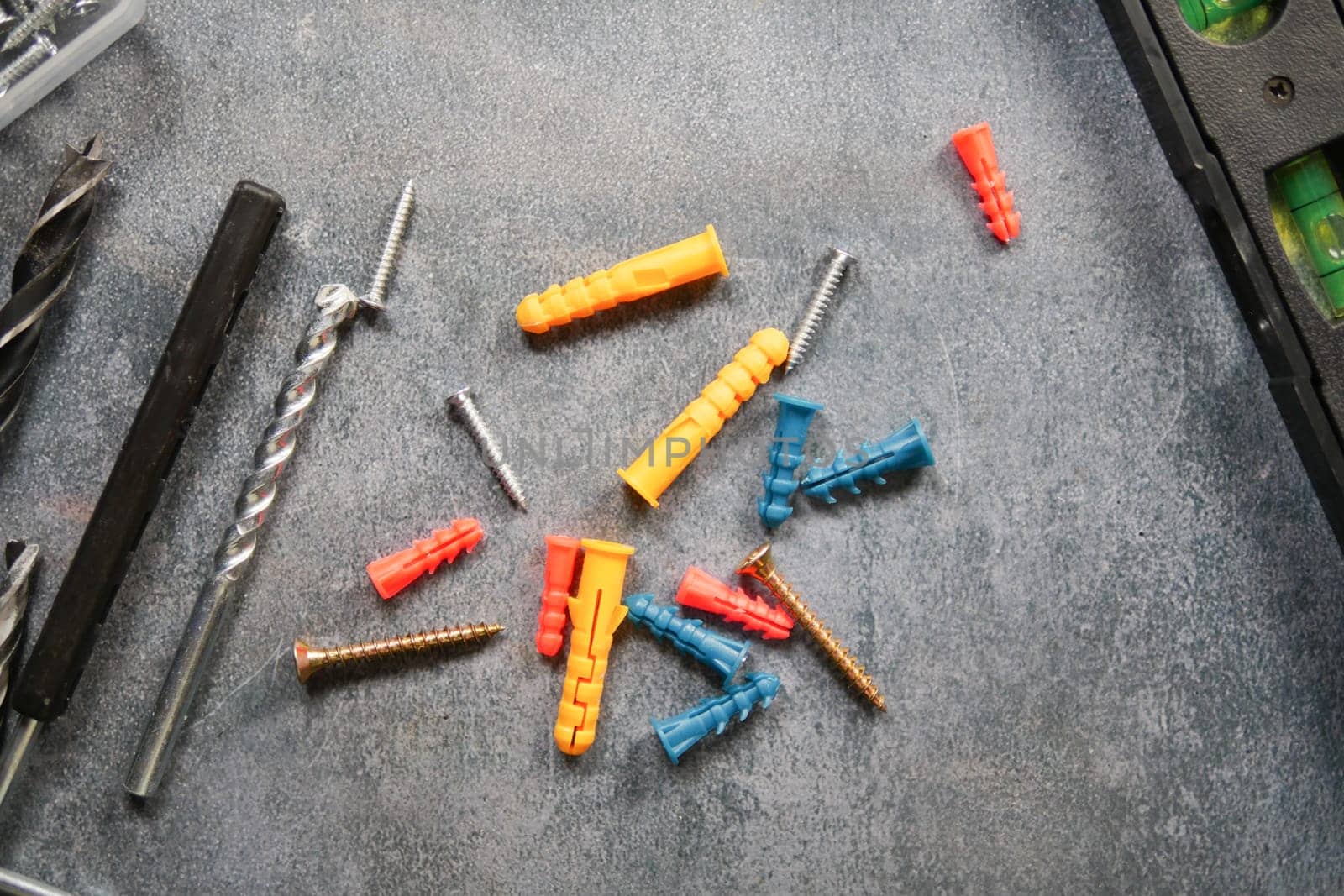 Tools and hardware pieces are arranged on a textured gray work surface.