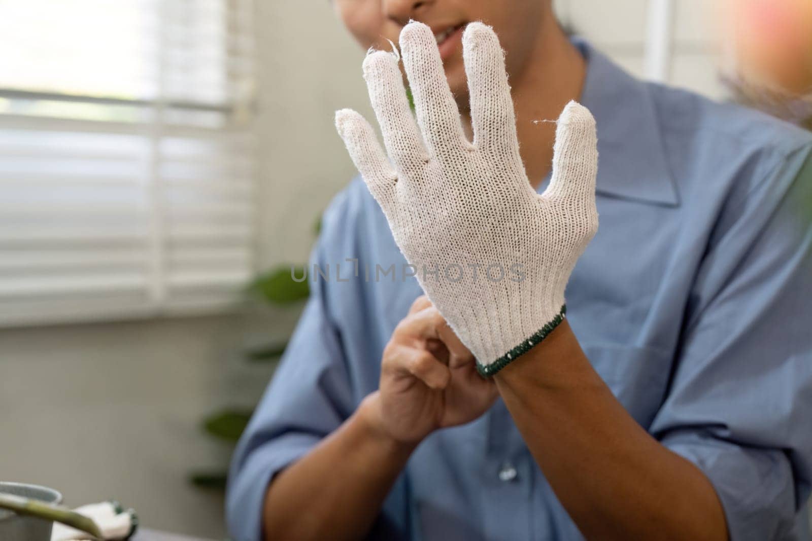 A person, dressed for gardening, proactively educates others on eco-friendly techniques, showcasing their protective gloves as they prepare for nurturing plants.