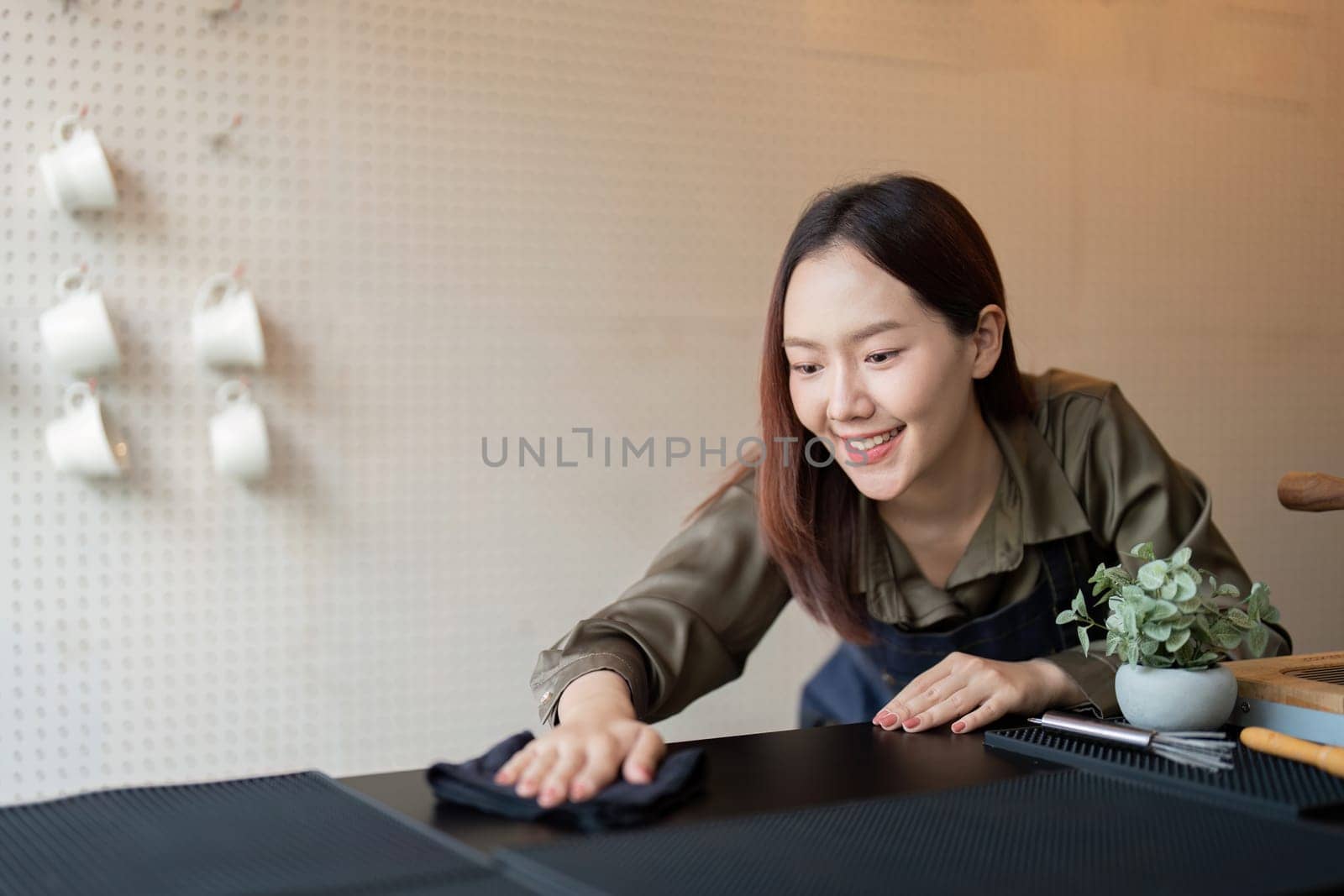 A barista smiles while cleaning the counter, showcasing her commitment to hygiene and a welcoming atmosphere in the sustainable cafe.