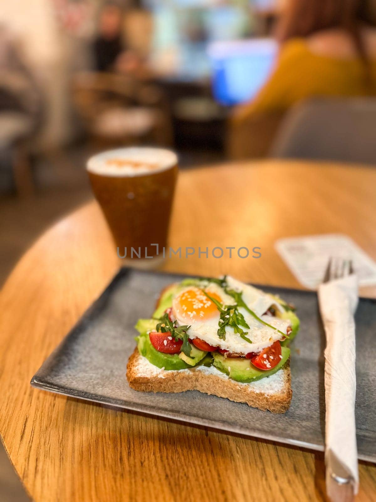 Avocado toast with egg served on a ceramic plate in cozy cafe. Healthy breakfast and balanced nutrition in a lifestyle setting