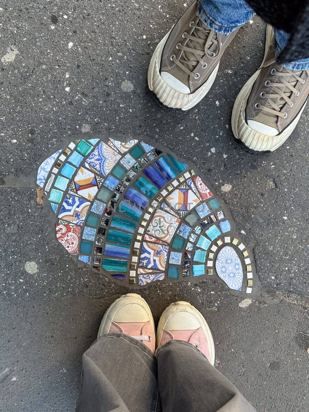 Two people standing by mosaic art on urban pavement. The image conveys the concept of spontaneous connection, artistic expression, and everyday beauty in city life