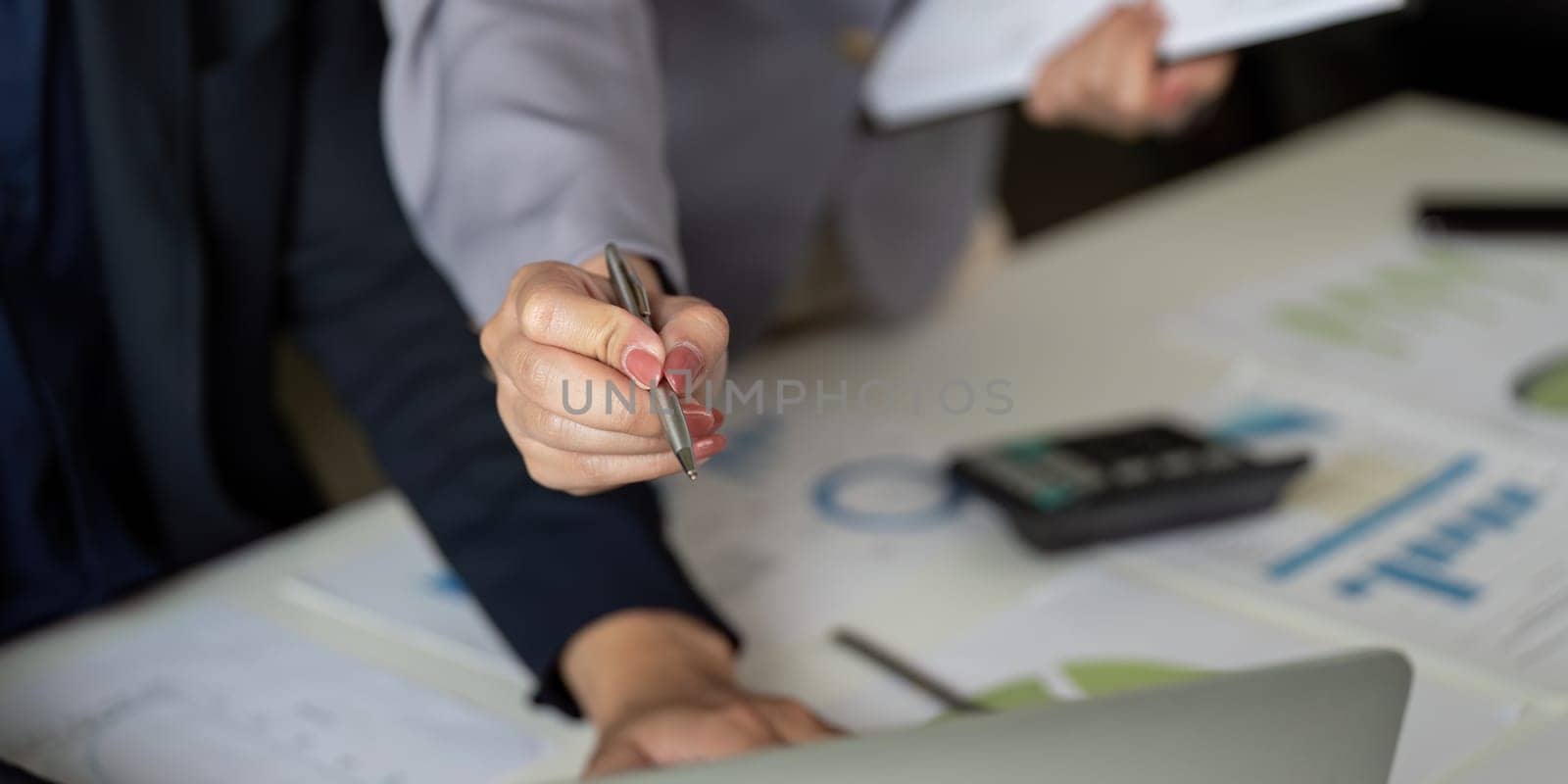 Professionals are analyzing data together, using a pen to highlight key areas in reports, emphasizing thoroughness in their review.