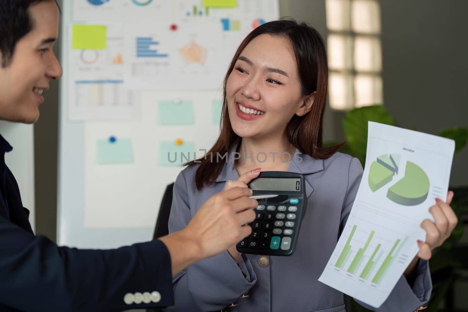 Two team members use a calculator and report to clarify data figures and share their insights effectively, fostering a collaborative work environment.