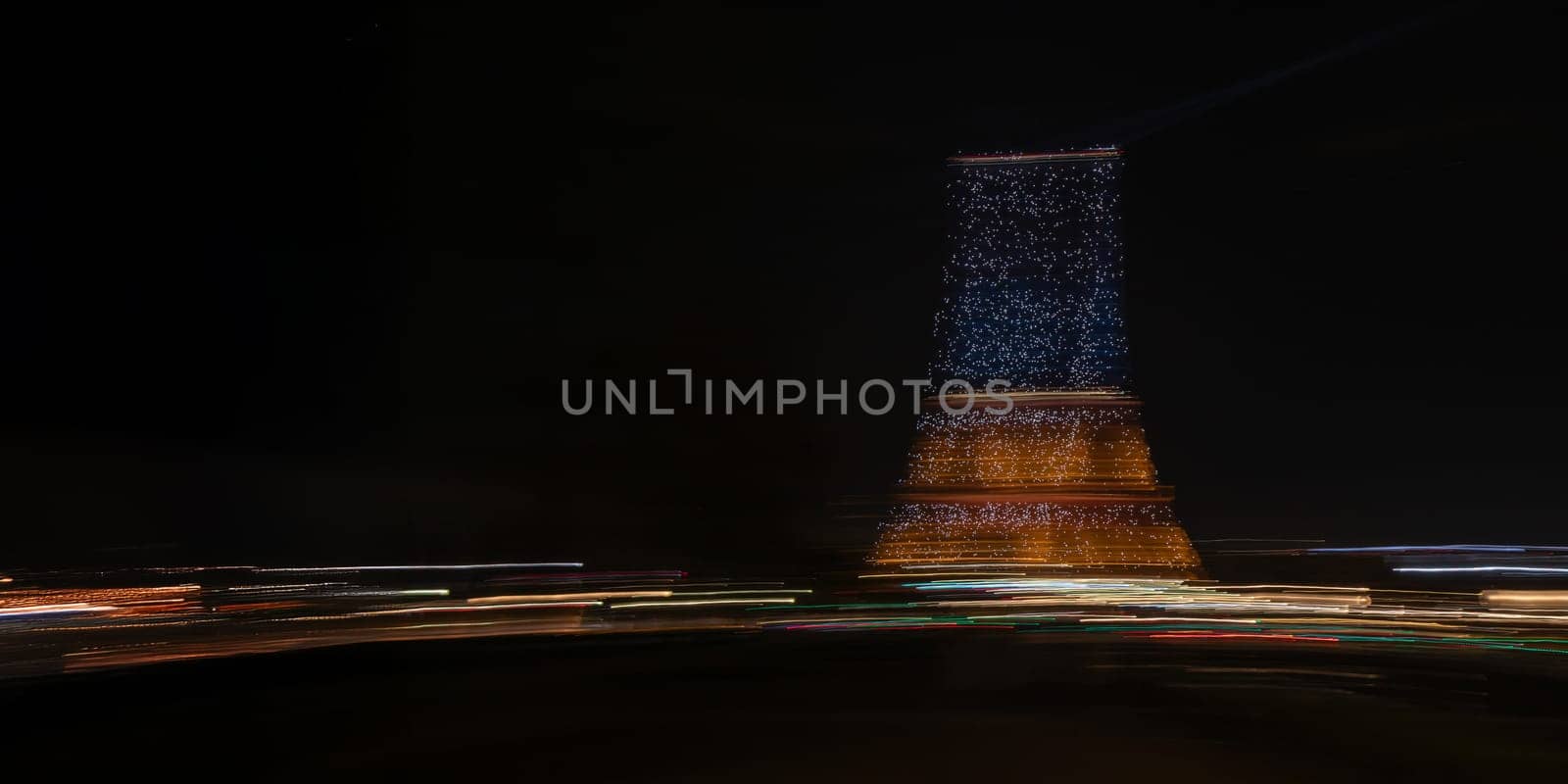Paris, France - February 24, 2025: the view of illuminated Eiffel Tower at night as streaks of light fill the scene, captured in motion with long exposure. Creative dynamic romantic background