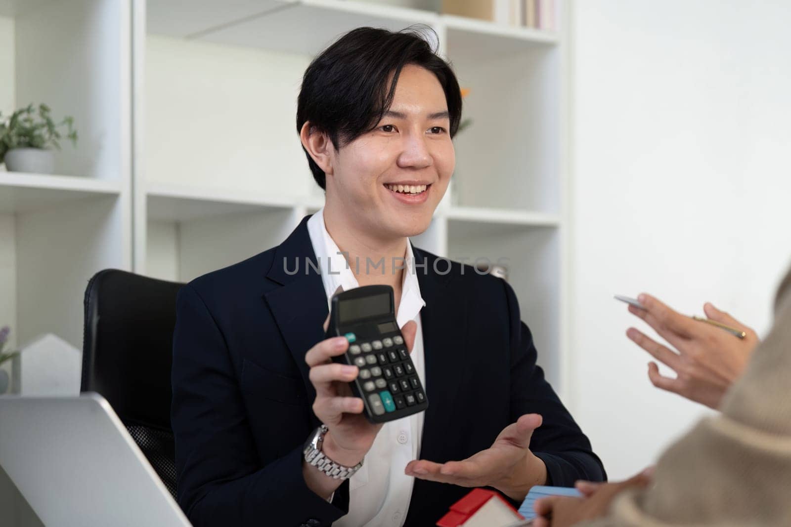 A friendly real estate agent engages in a conversation about property investment, showcasing the use of a calculator to clarify financial aspects.