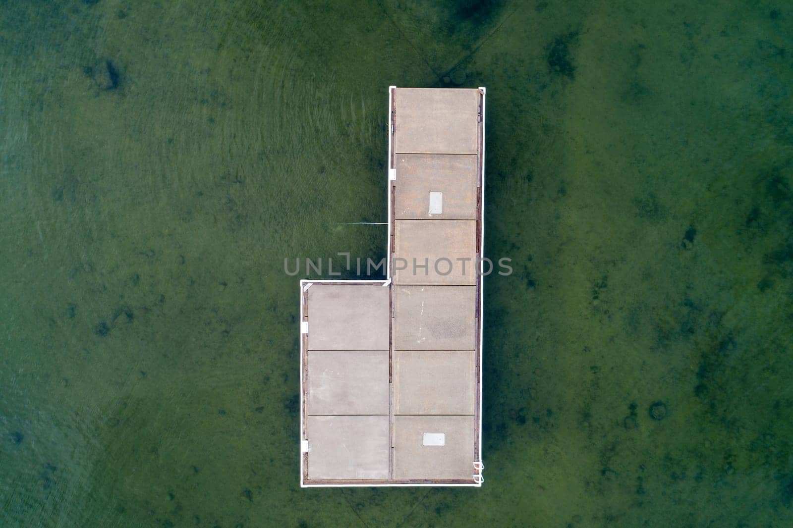 A dock is shown in the water with a view of the sky. The dock is empty and the water is green