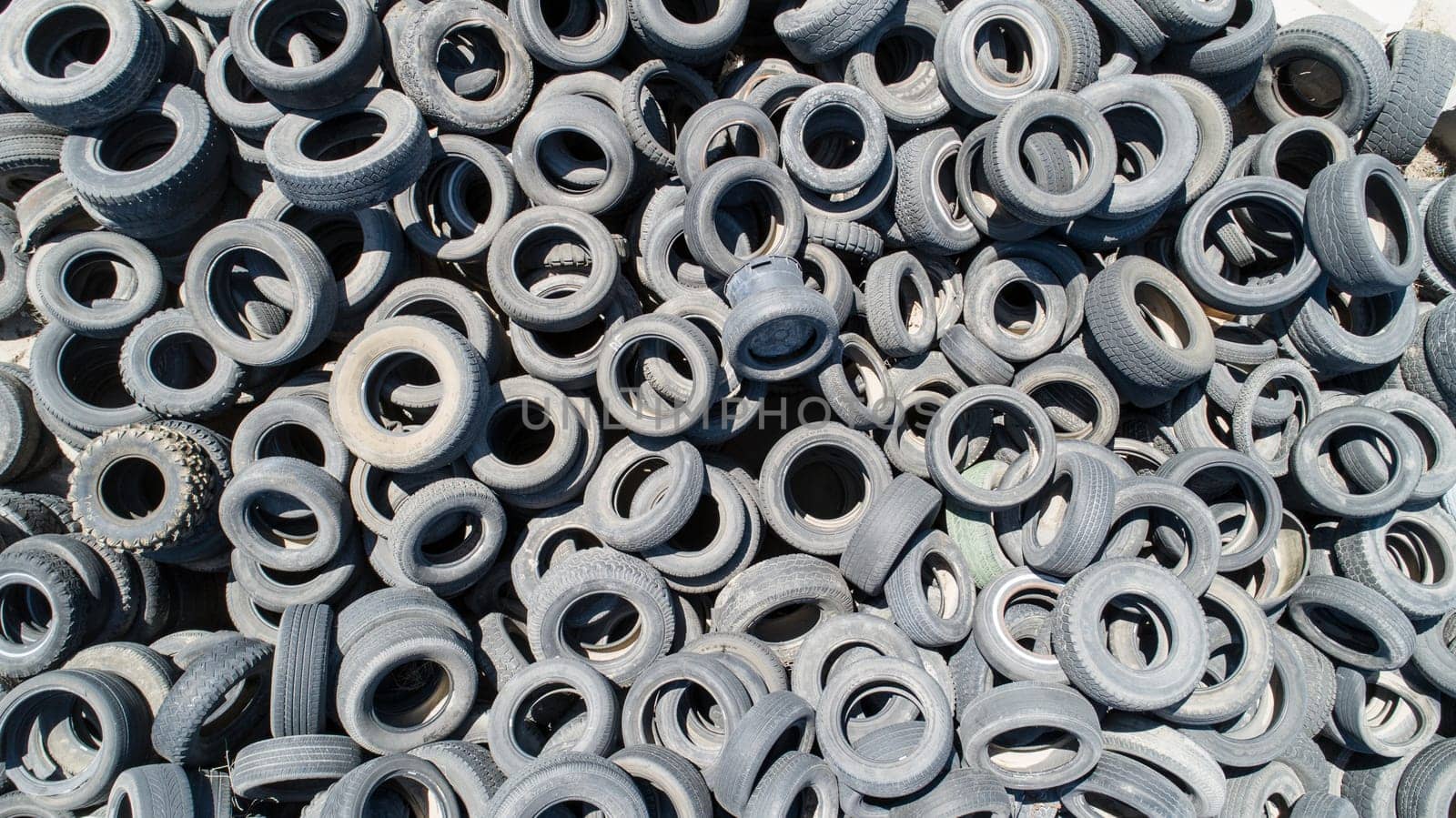 A pile of old tires with a lot of different sizes. The tires are all different colors and sizes, and they are piled on top of each other. Concept of waste and disorganization