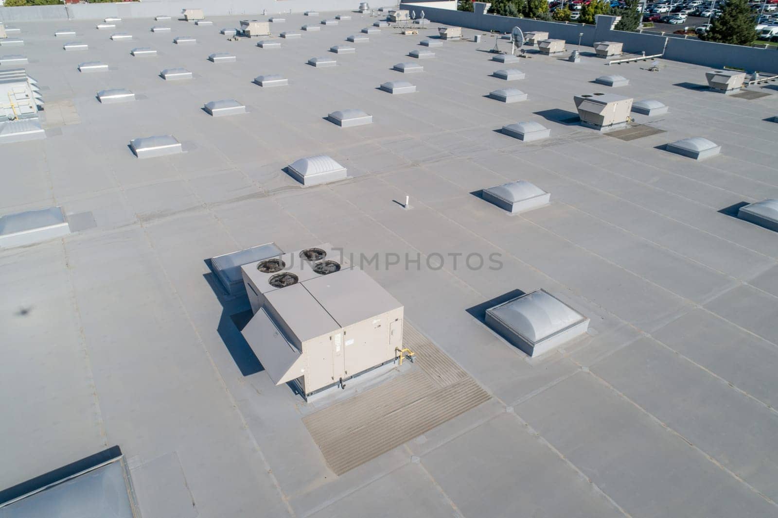 A large building with many vents and a large air conditioner. The vents are all different sizes and are spread out across the roof