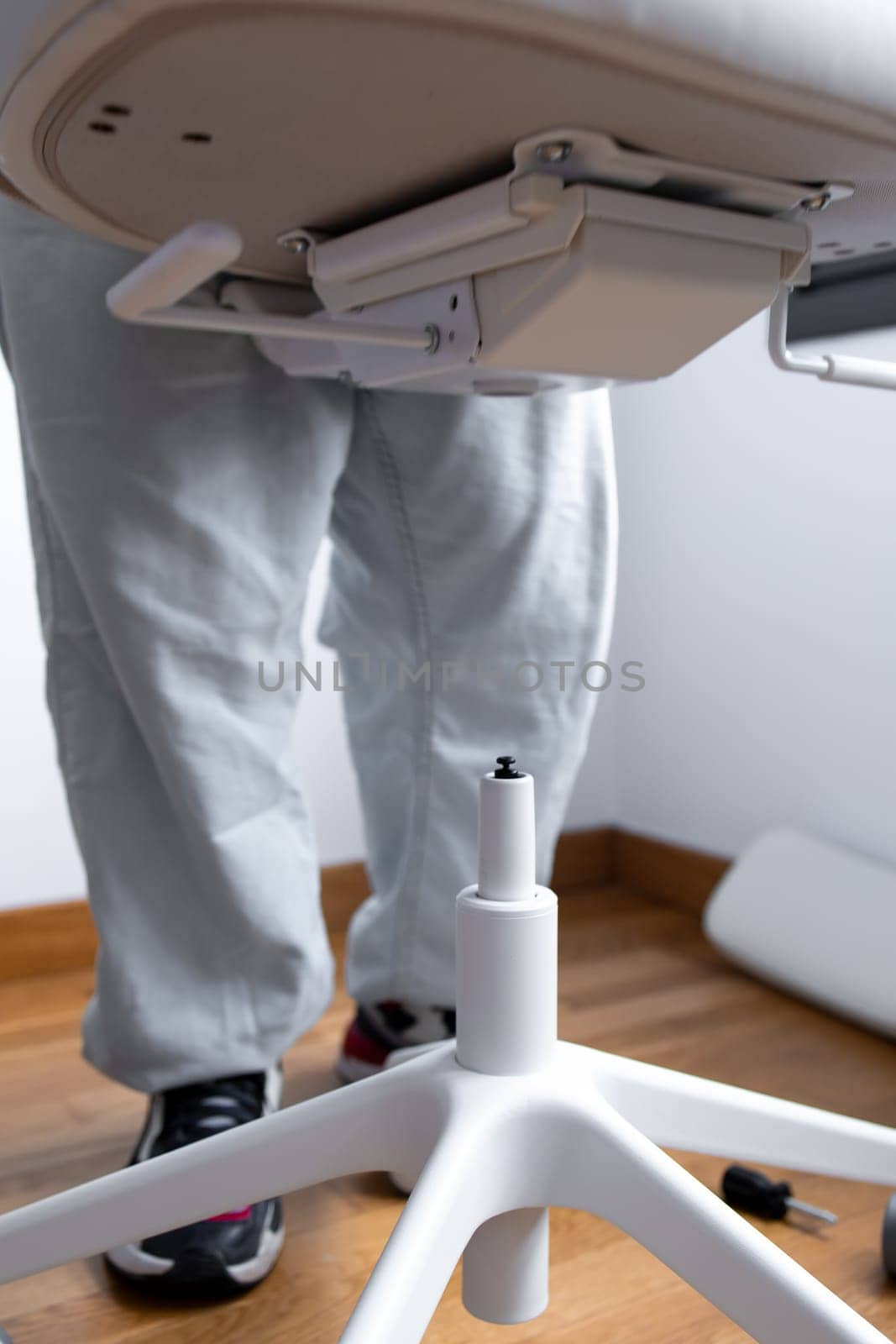 Man assembling office chair base in room with wooden floor.