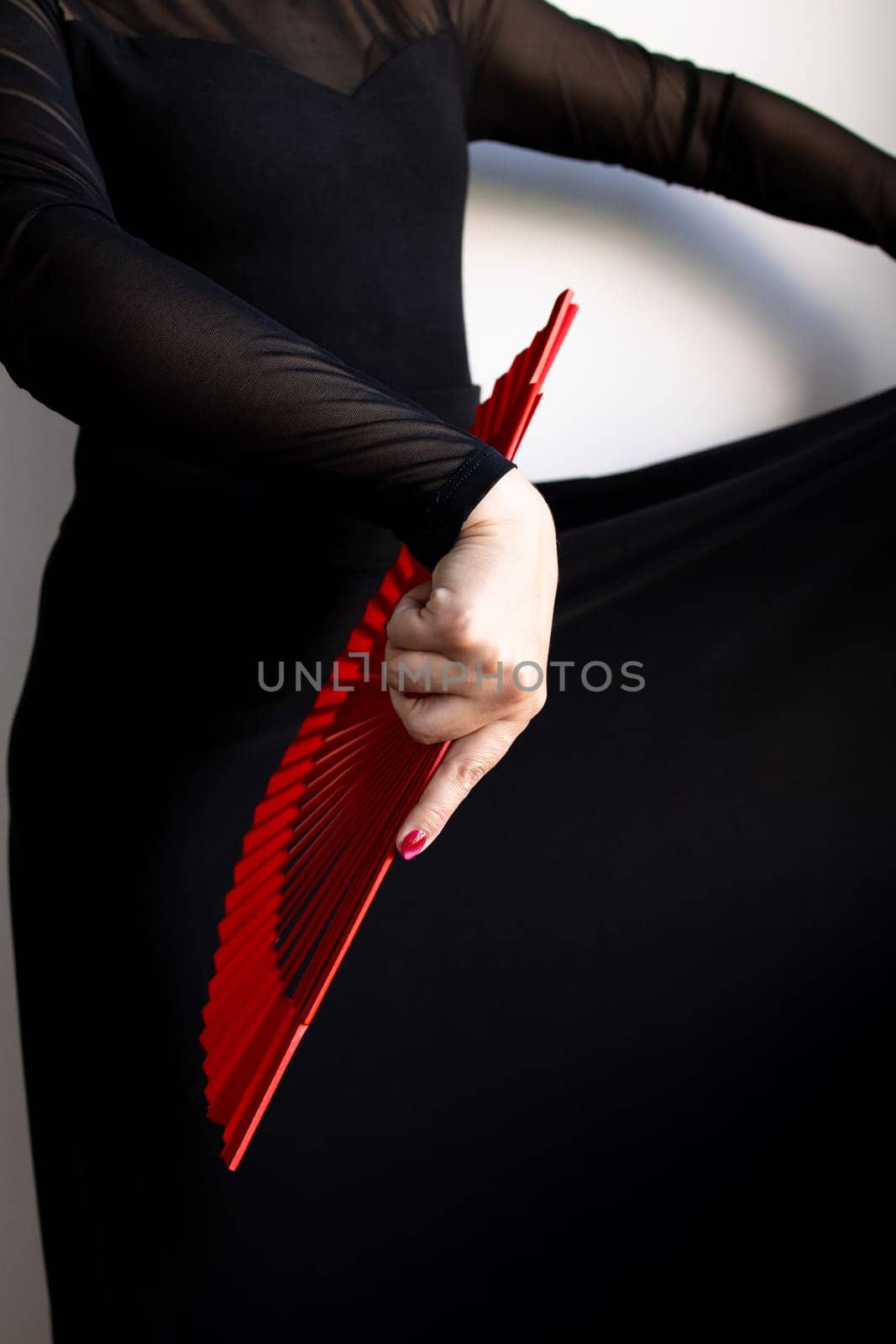Female performer with red fan and black dress in motion.