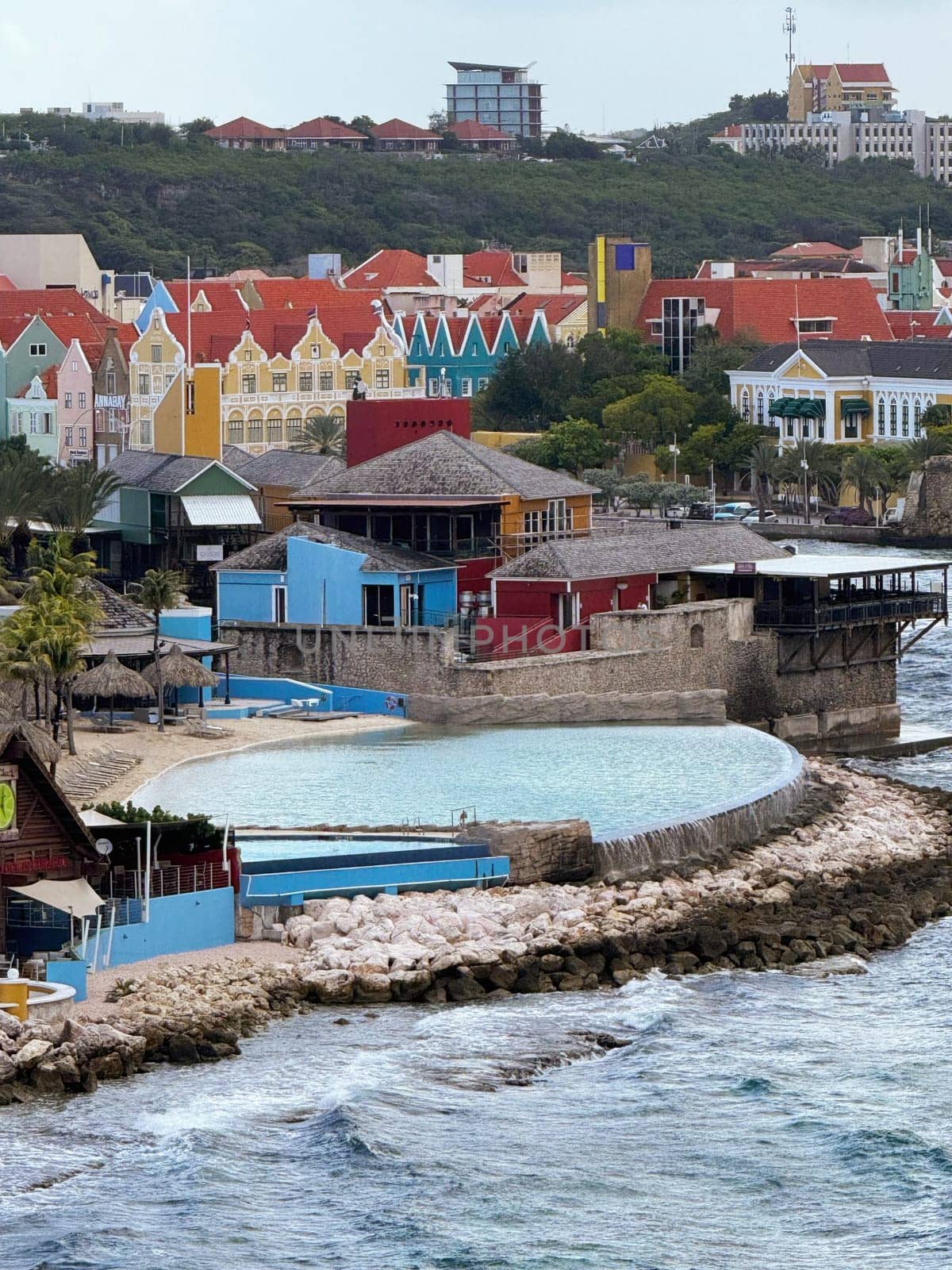 Willemstad, Curacao 10.22.2023 A pair of modern cruise ships are moored at a long concrete pier on a sunny tropical island. Clear blue sky and calm sea create an ideal setting for travel and vacation