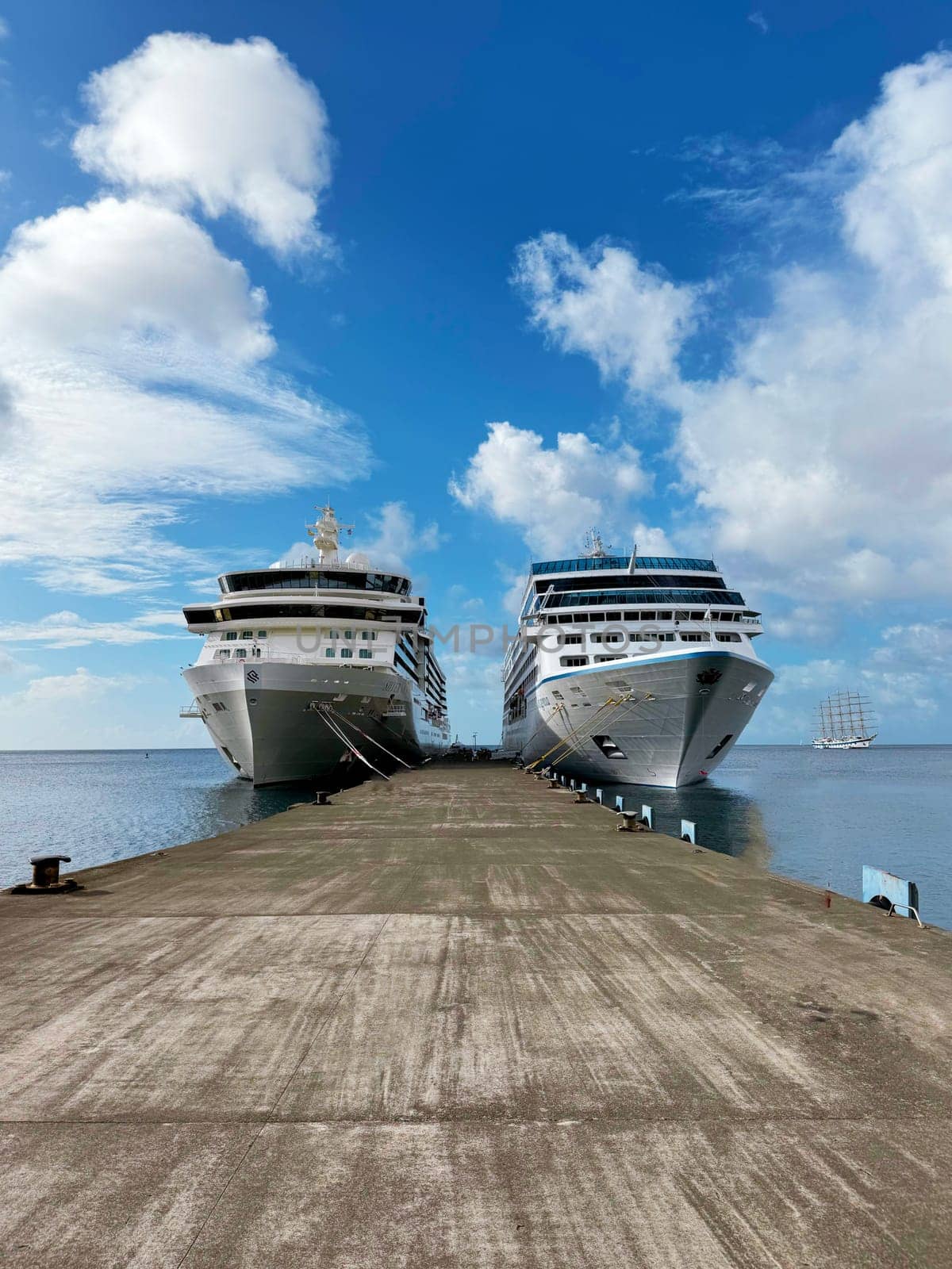 Bermuda, U.S. 10.22.2023 A pair of modern cruise ships are moored at a long concrete pier on a sunny tropical island. The clear blue sky and calm sea create an ideal setting for travel and vacation.