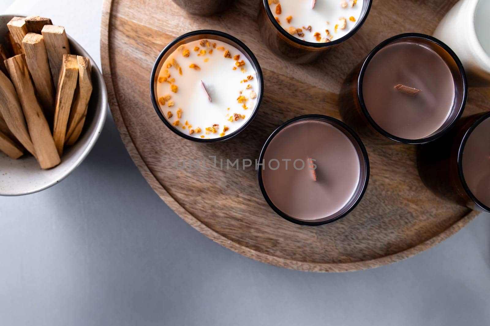 Aromatic scented candles with wooden wicks on round tray.