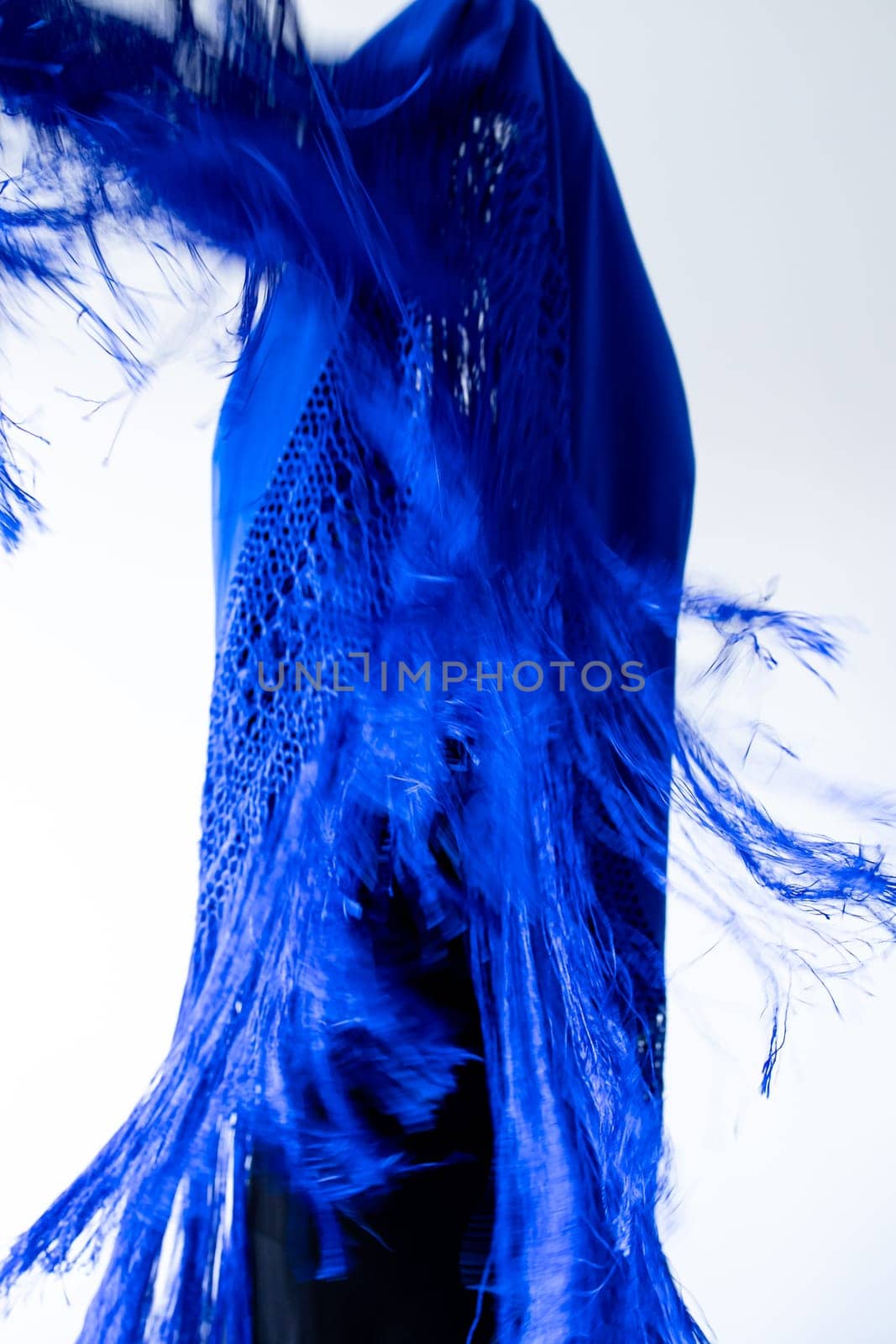 Dynamic blue fabric movement with fringe detail against white background.