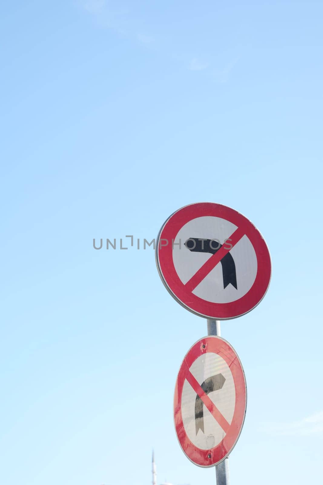 No U turn signs against a clear blue sky in a traffic area,