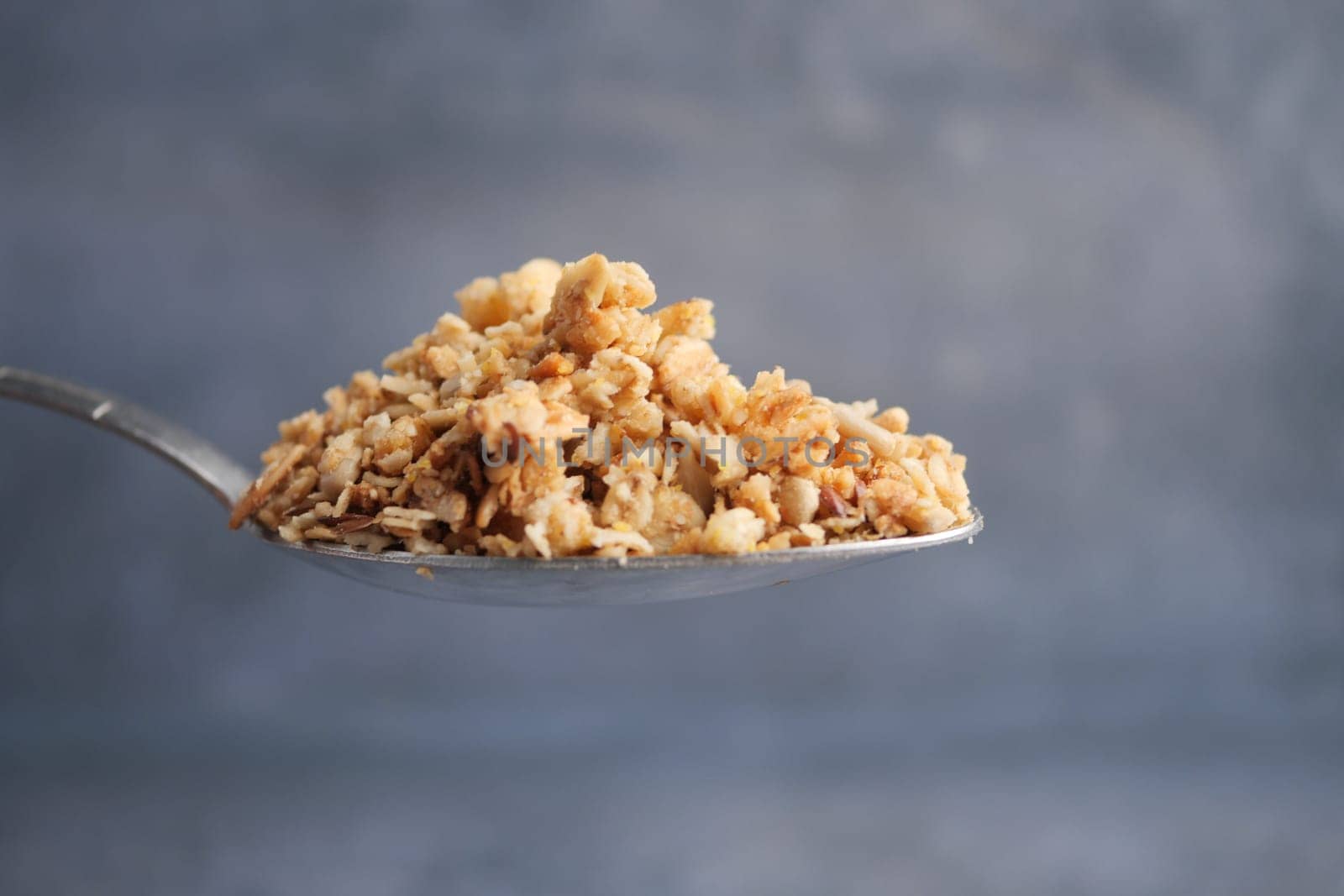 Granola on a silver spoon highlights its crunch and color.