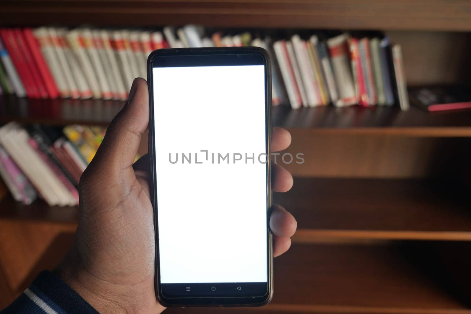 User shows a blank smartphone screen next to nearby books.