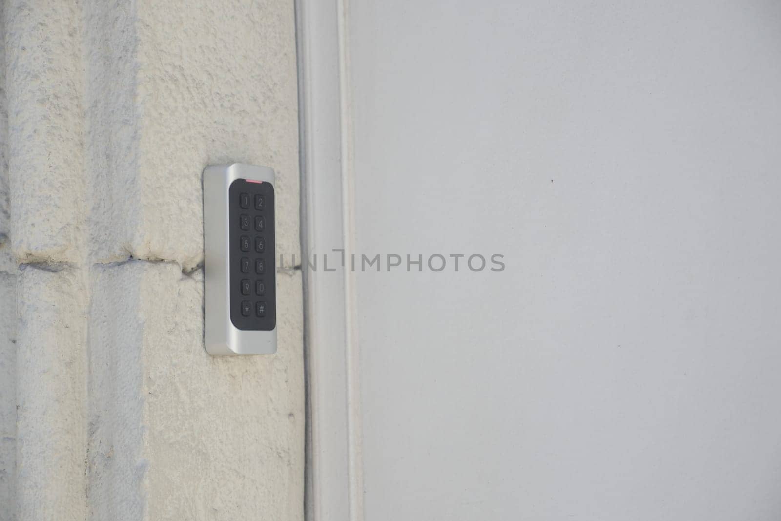 Access control device features a numeric keypad on a concrete wall.