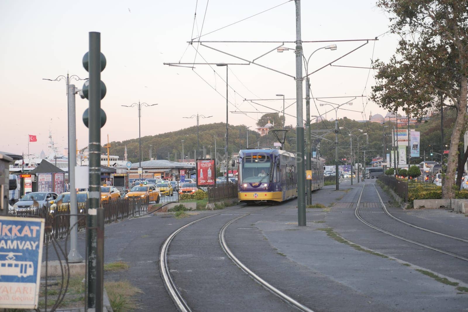 Tram moves along the tracks as day transitions to night in the city.
