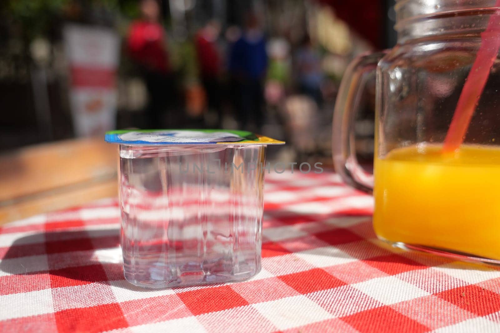 A vibrant orange drink is placed on a table with a checkered cloth.