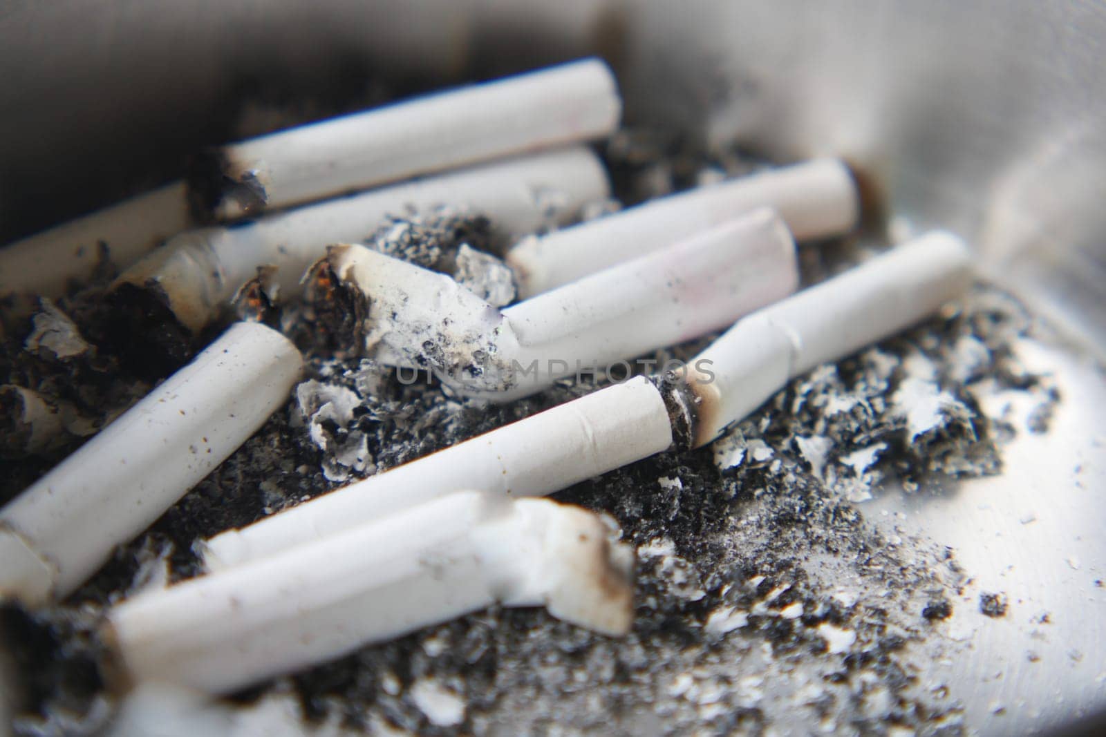 Butts remain in an ashtray, indicating a recent social event or gathering.