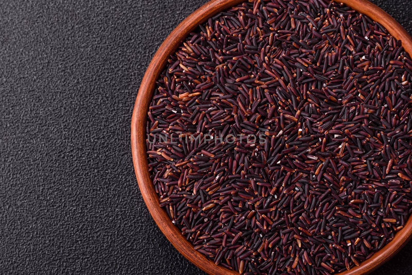 Red or brown raw rice in a ceramic bowl. Rice as an ingredient in Asian organic food