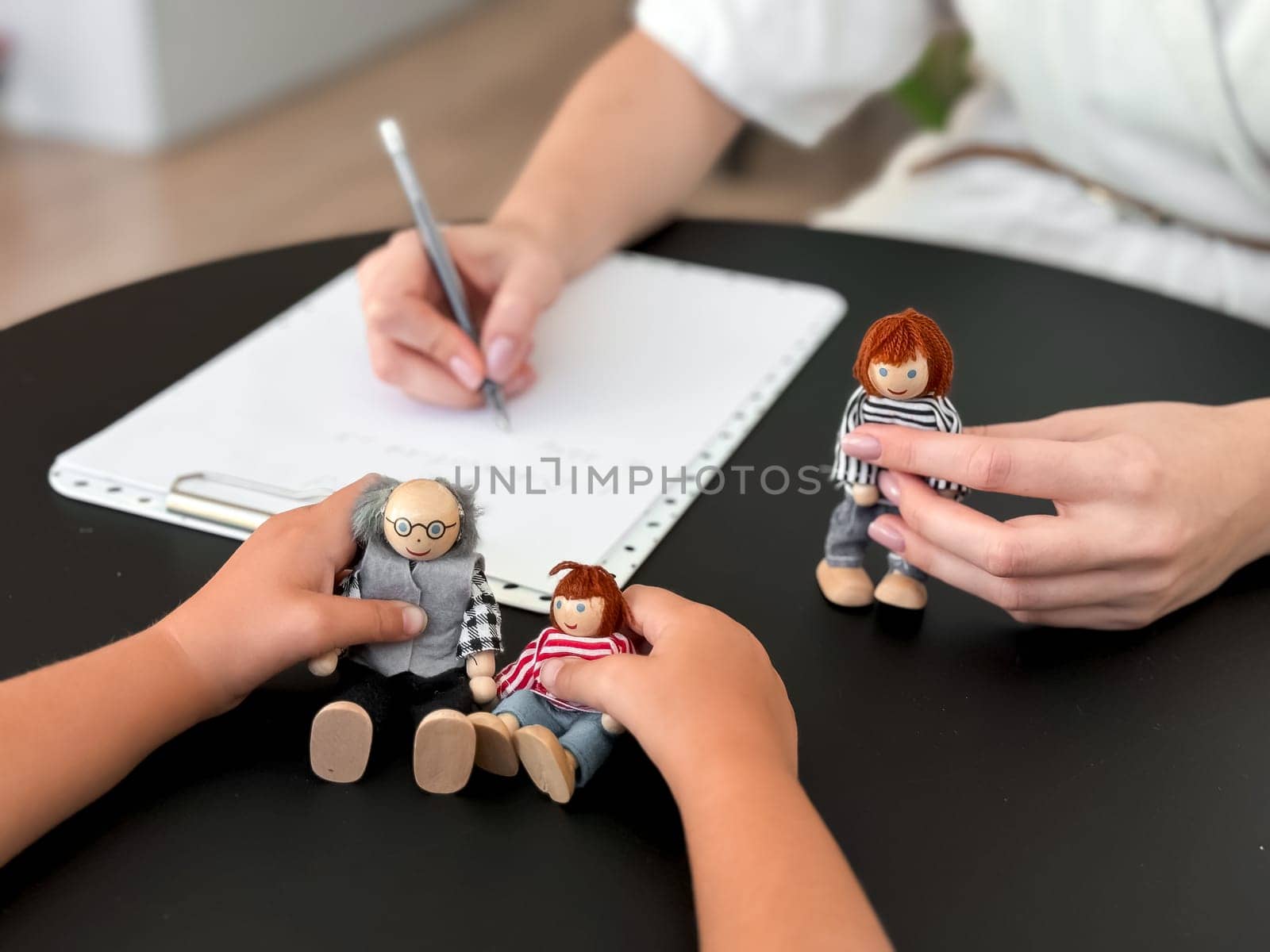 Child therapy session with caucasian female therapist using dolls for emotional expression.