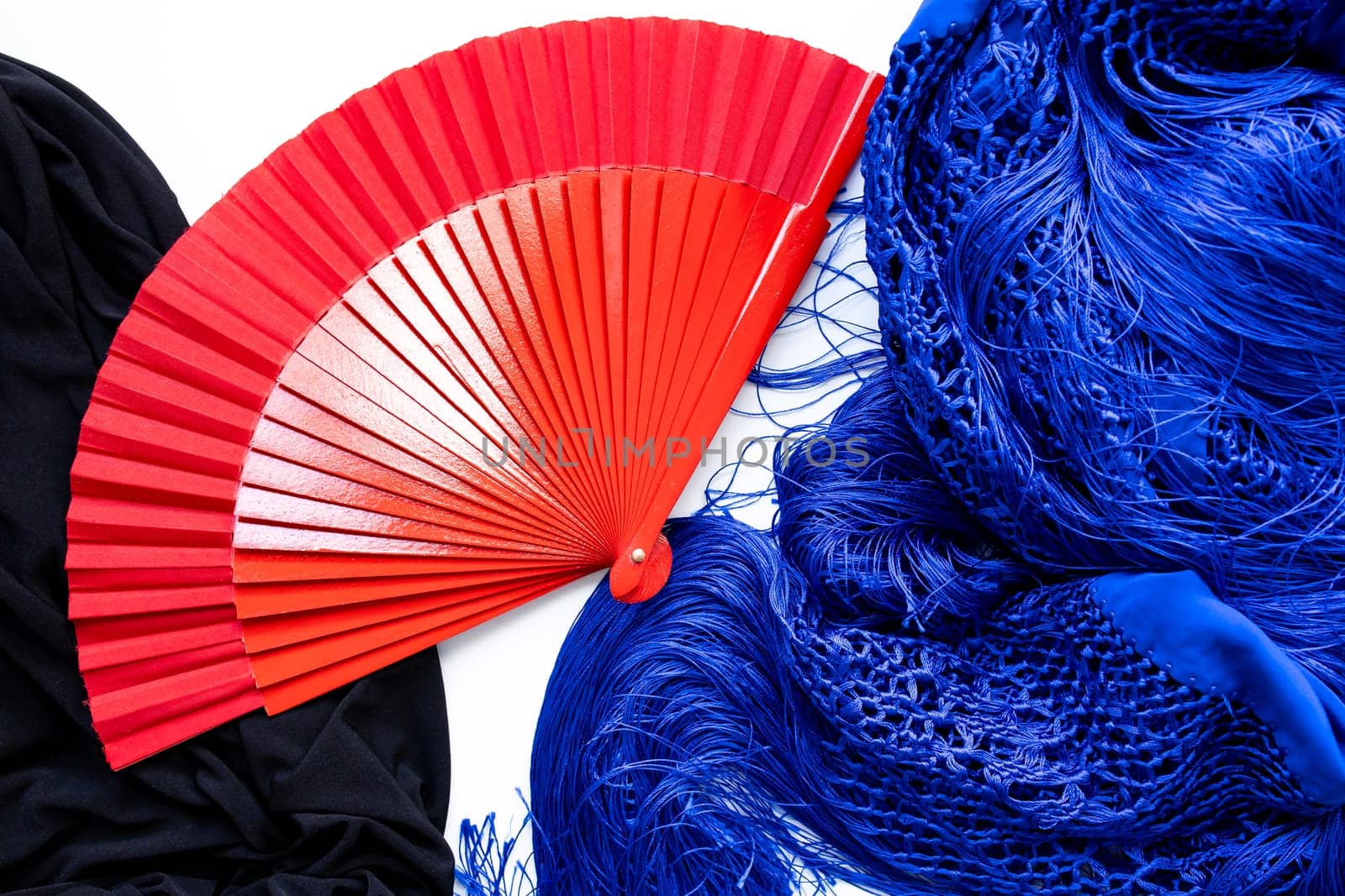 Red fan with blue and black flamenco shawls on white background.
