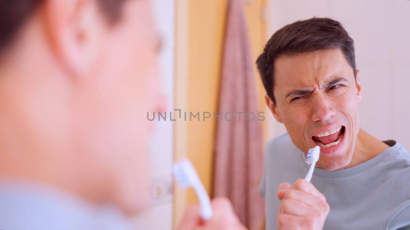 Man using toothbrush as microphone while singing in front of bathroom mirror