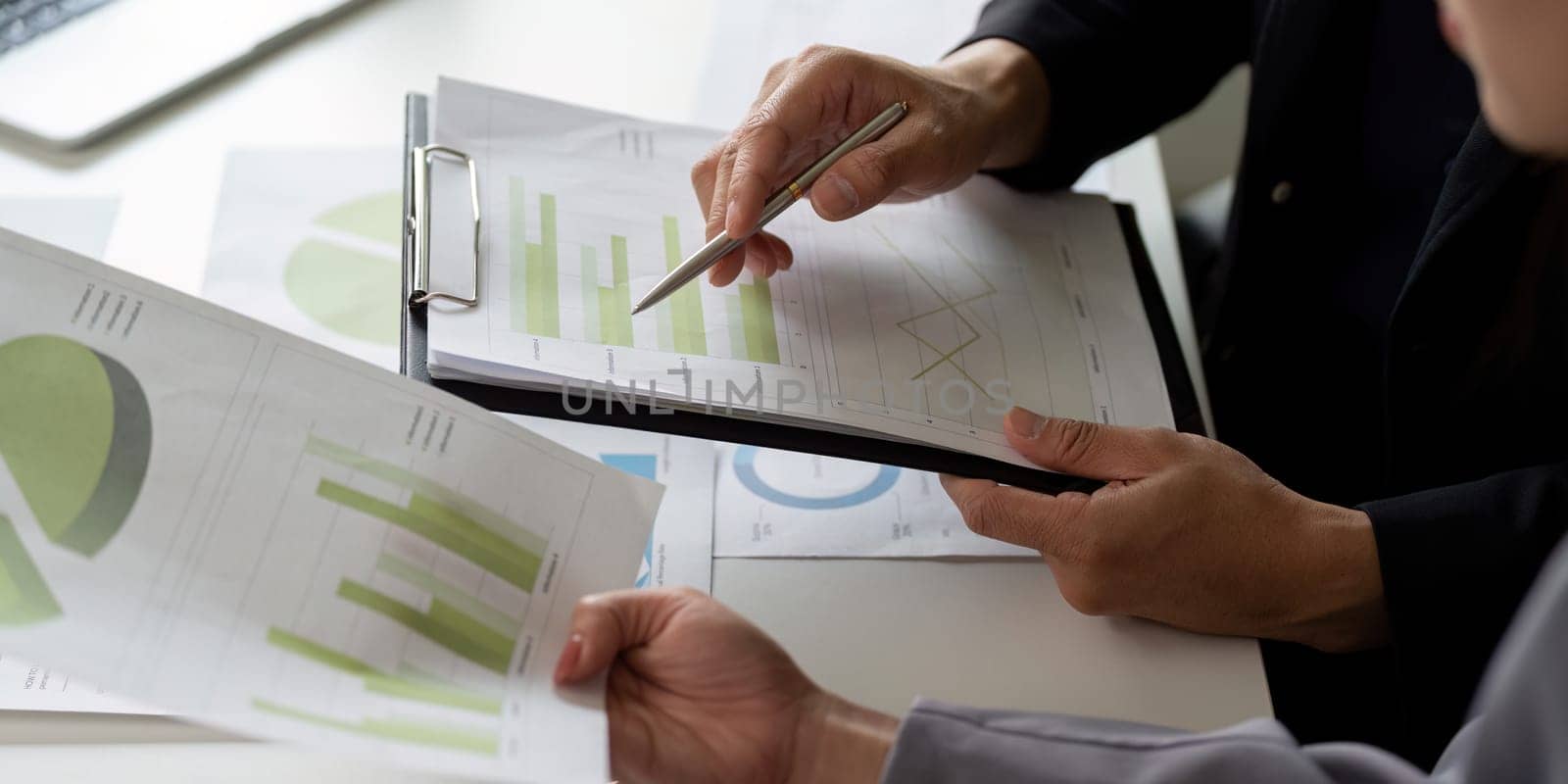Team members are engaged in a collaborative discussion about business data, reviewing charts and graphs to make informed decisions during a brainstorming session.