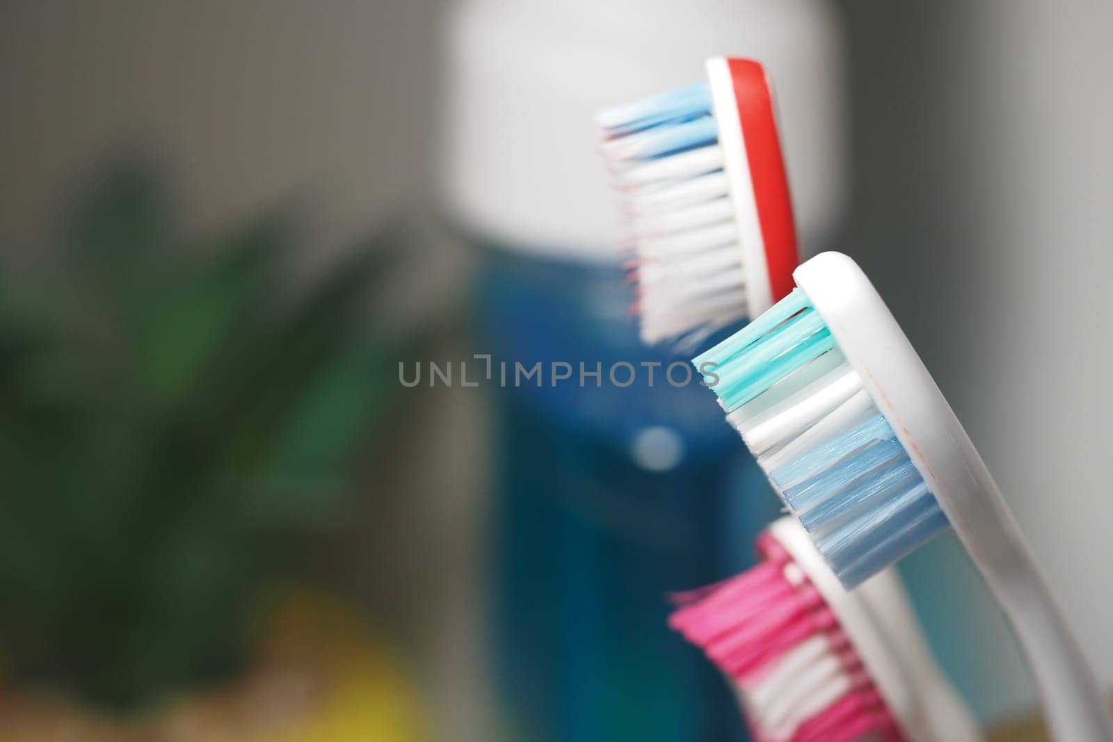 Three vibrant toothbrushes are arranged beside a bottle of mouthwash.