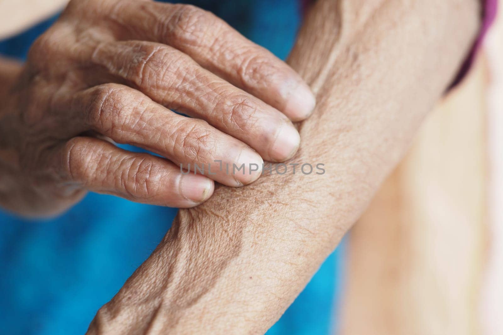 Elderly hand gently touches the arm, showcasing age and texture in daylight.