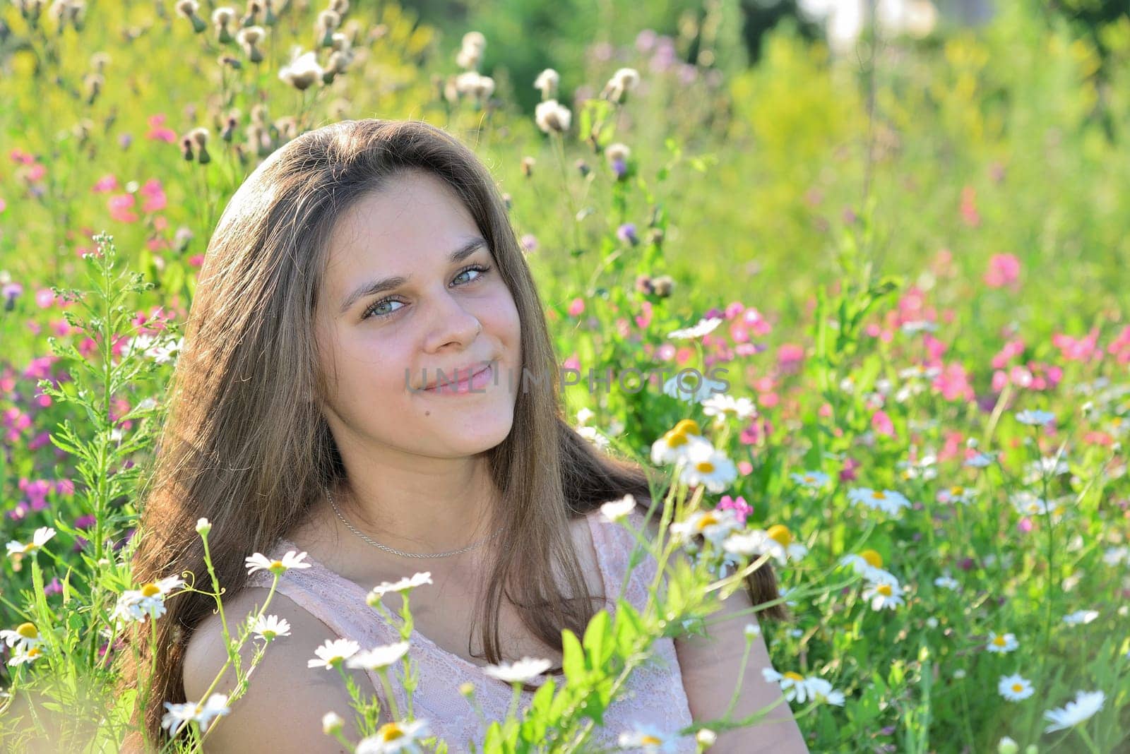 Happy 16 year old girl surrounded by a blooming field