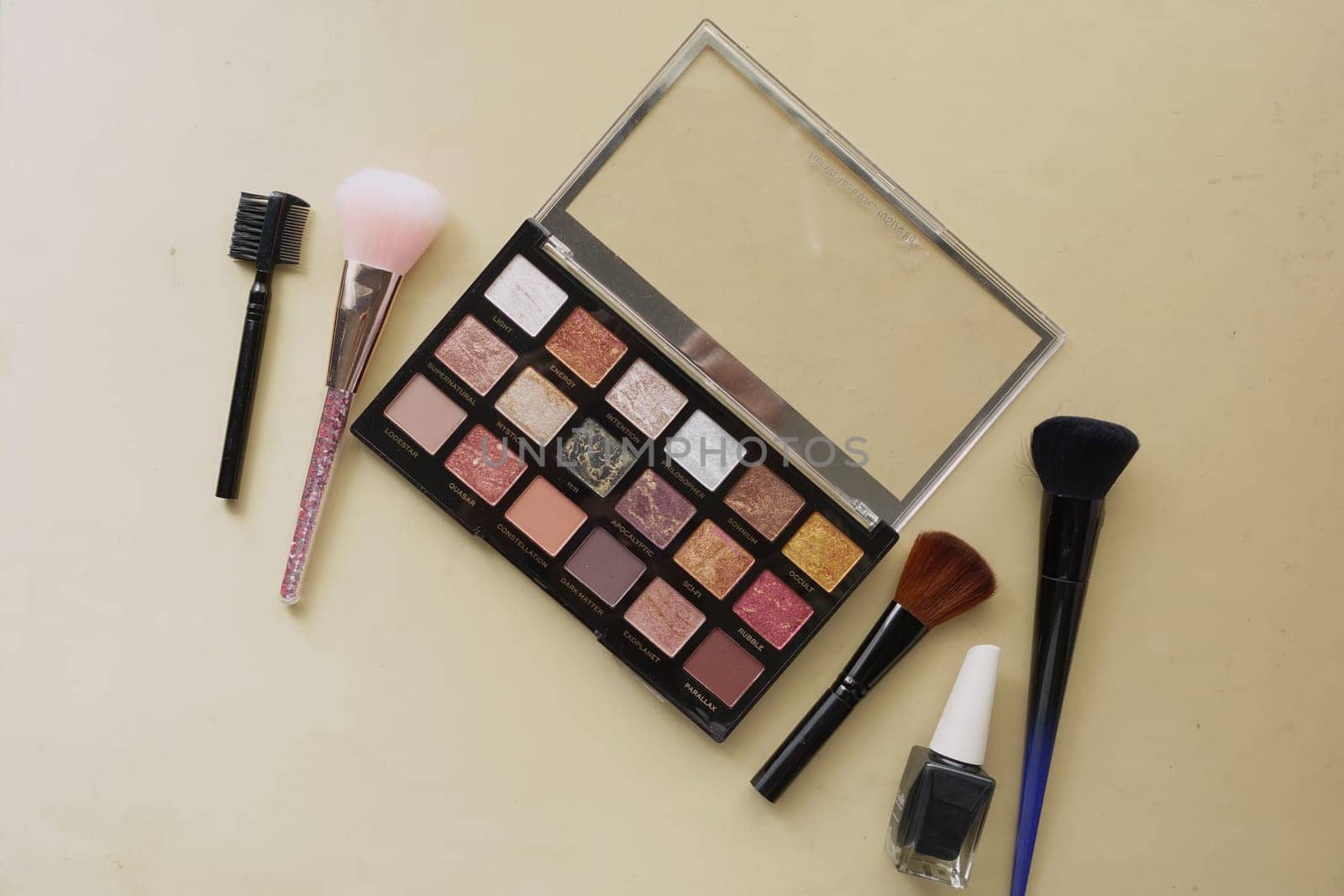 Colorful eyeshadow palette and makeup brushes displayed on a table surface.
