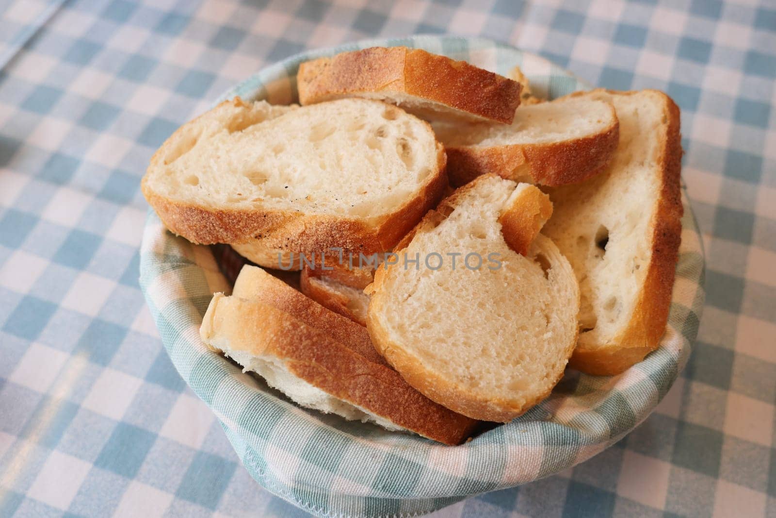 Slices of freshly baked bread arranged in a basket on a checkered tablecloth.