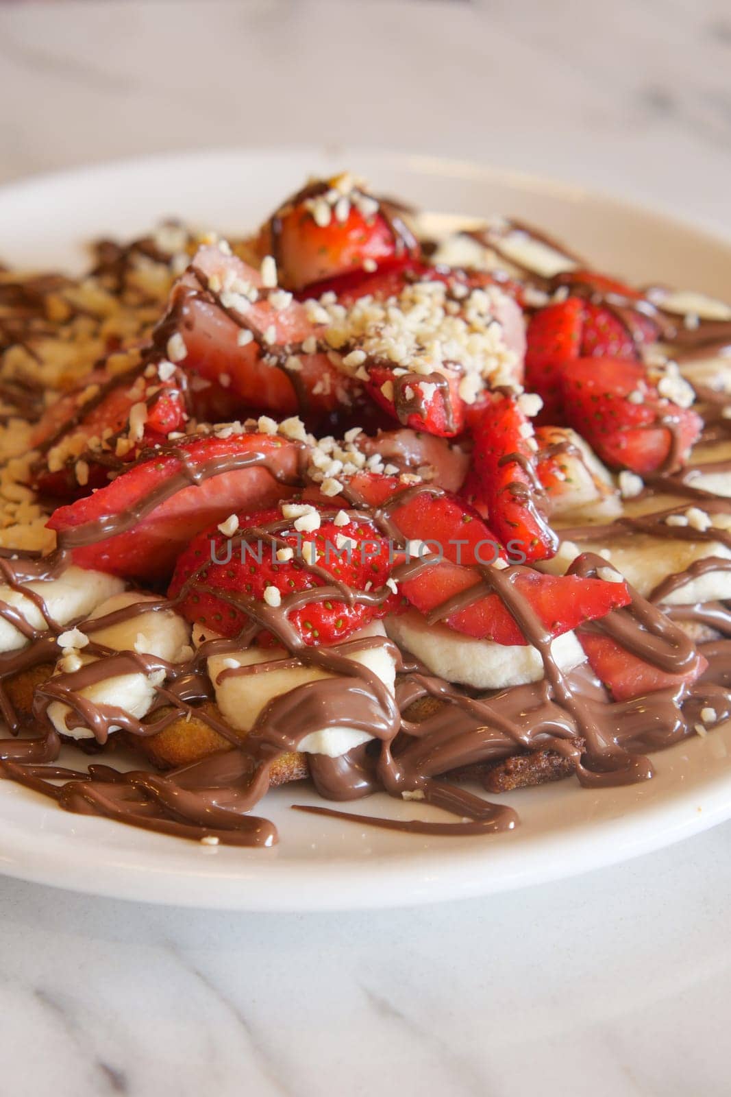 A dessert plate featuring strawberries, bananas, and chocolate drizzle.