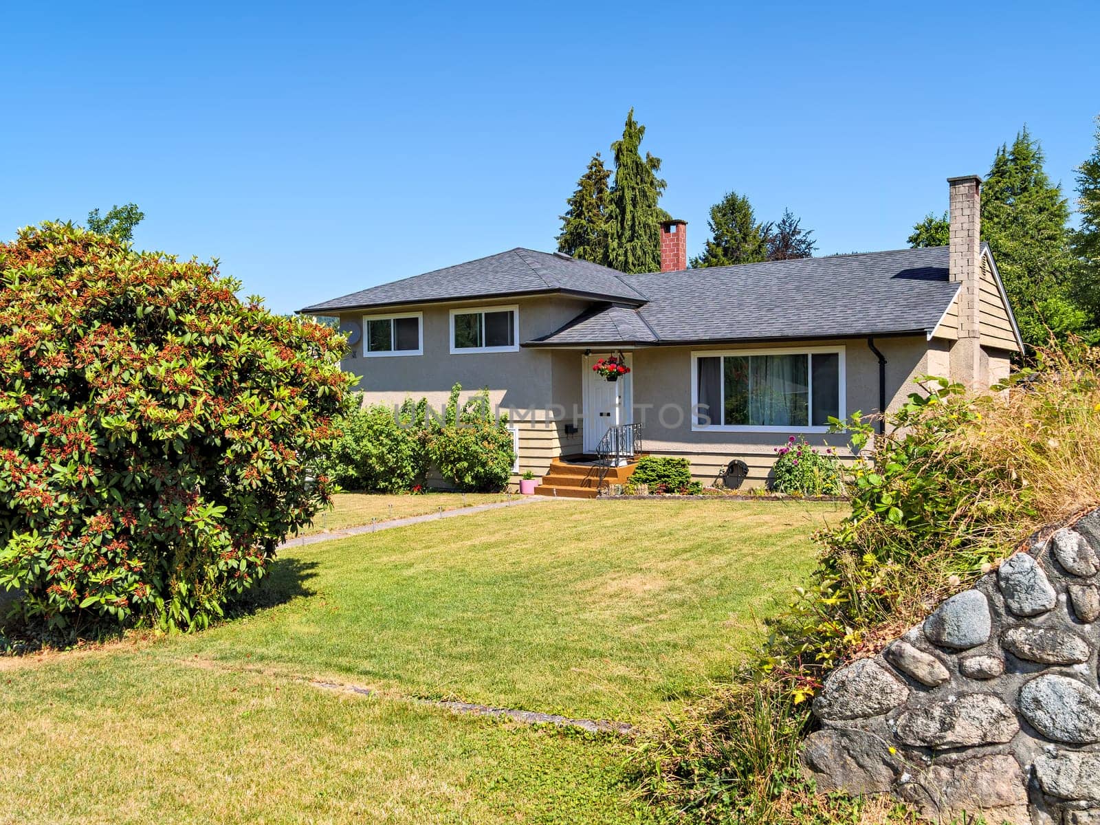 A perfect neighborhood. Neat residential house with concrete doorsteps and pathway to the entrance over front yard lawn