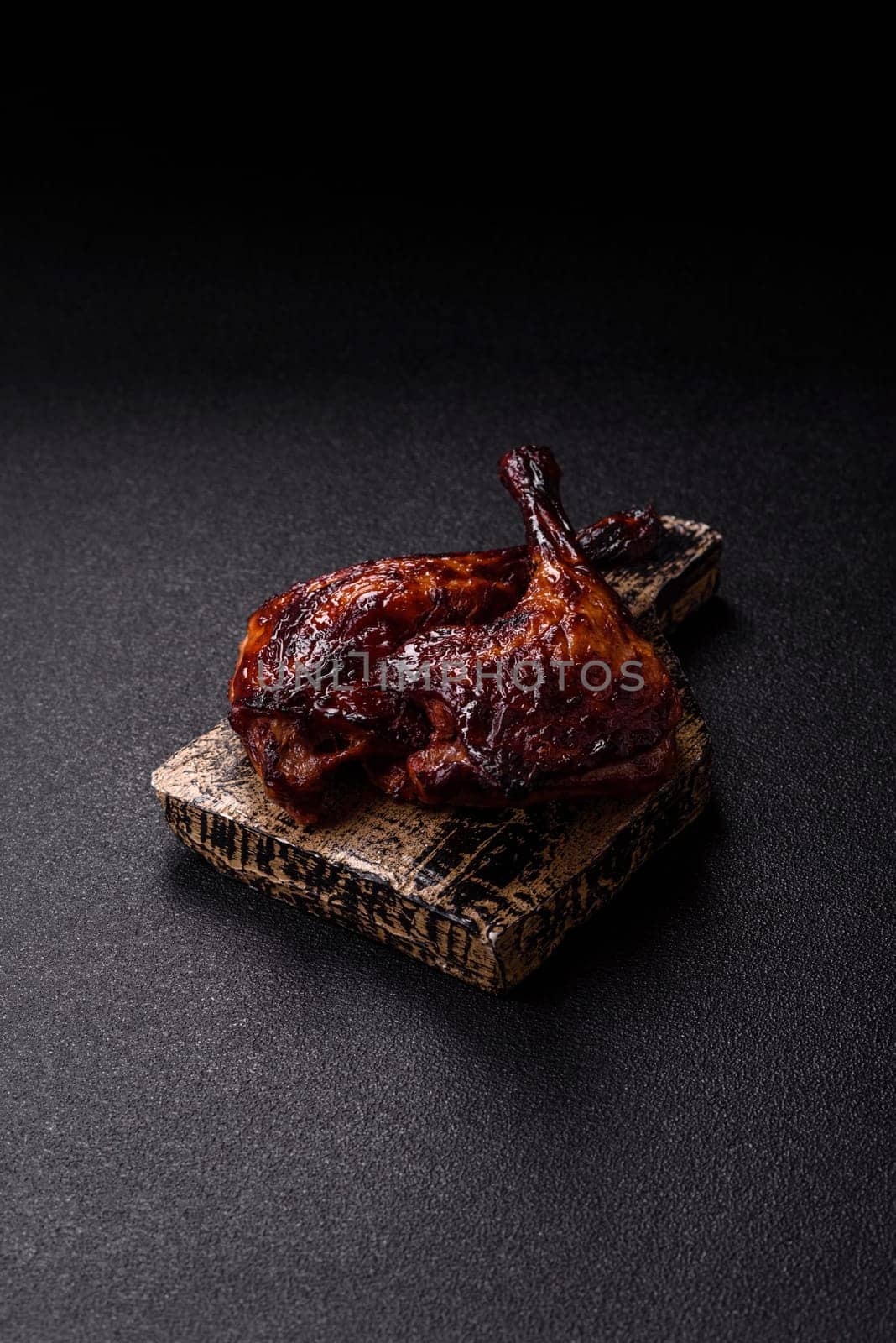Duck, chicken leg or thigh grilled on a dark concrete background. Duck confit, Asian food with salt and spices