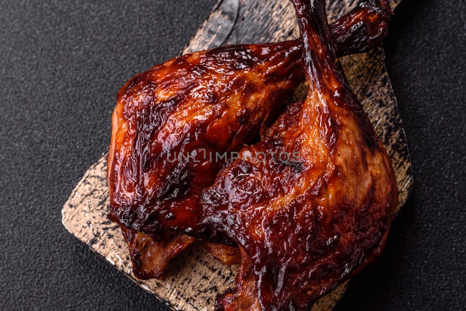 Duck, chicken leg or thigh grilled on a dark concrete background. Duck confit, Asian food with salt and spices